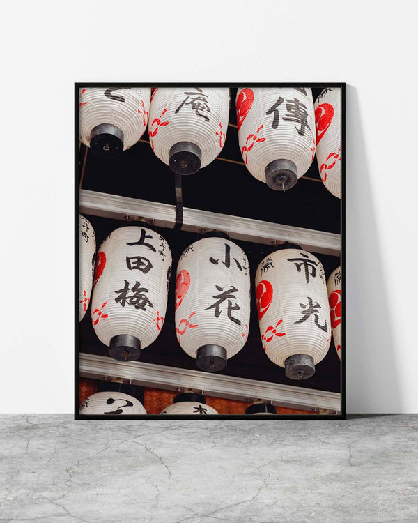 Close-up of traditional Japanese paper lanterns with bold black calligraphy and red accents, hanging in a row.