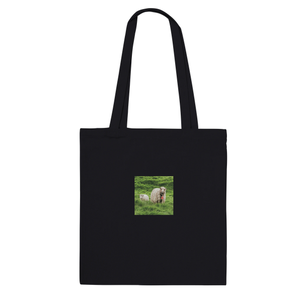 Black tote bag featuring a centered print of a sheep and lamb in lush green grass.