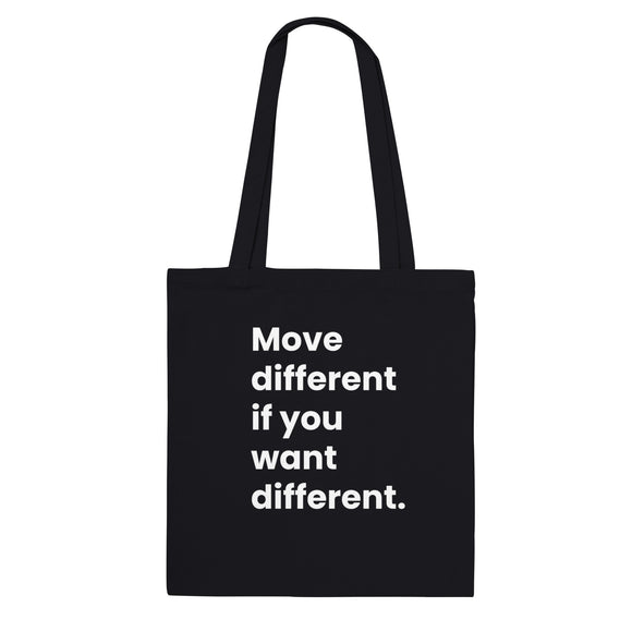 A black canvas tote bag designed by North Minimal featuring white letter text that reads "Move different if you want different.". The image shows the front of the tote bag with the text centered and clearly visible on the black background.