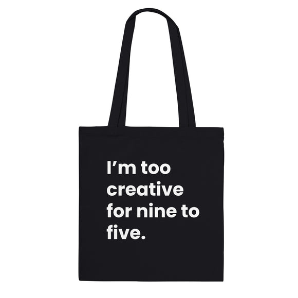 A black canvas tote bag designed by North Minimal featuring white letter text that reads "I'm too creative for nine to five.". The image shows the front of the tote bag with the text centered and clearly visible on the black background.