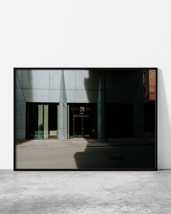 A modern architecture photo print in a black frame, designed by North Minimal and showcasing the stunning contemporary architecture of Copenhagen. The photograph captures the sleek lines and geometric shapes of a unique building, with a minimalist design that emphasizes the beauty of simplicity. 