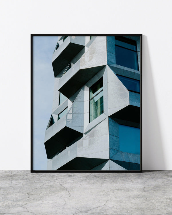 A photo of a modern building in Copenhagen, designed by North Minimal, featuring clean lines and a unique, minimalist design. The photo is displayed in a black frame, creating a bold and contemporary art piece